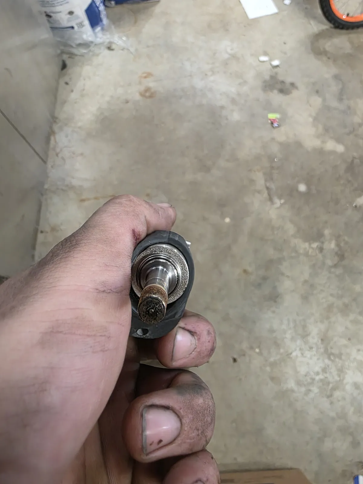 A fuel injector held in a hand, its tip and ports crusted over with corrosion