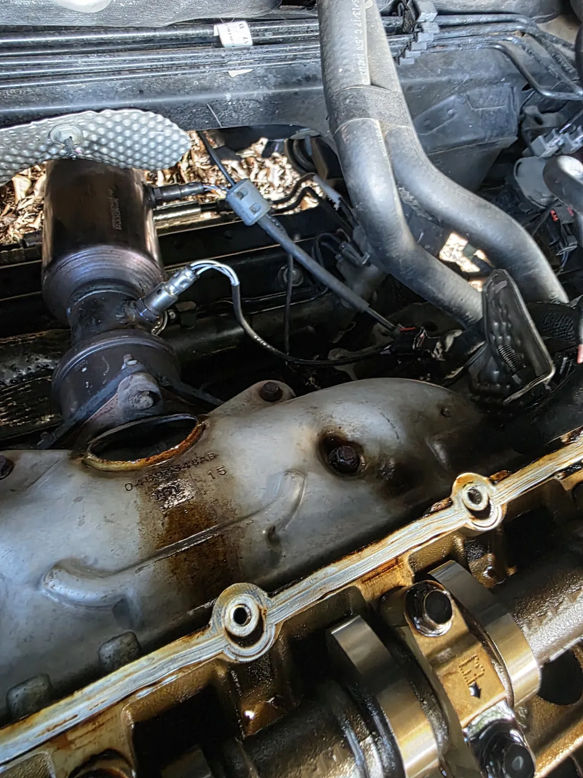 Oil stains on an exhaust manifold beside a cylinder head with its valve cover off